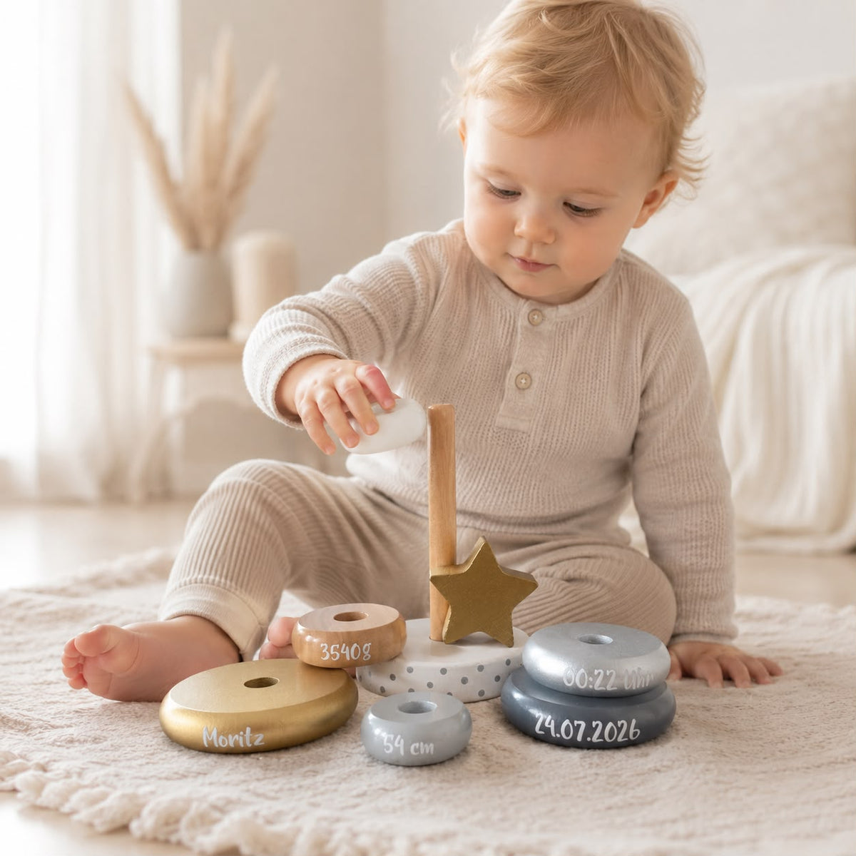 Baby spielt mit einem personalisierten Holz-Stapelturm mit Geburtsdaten. Liebevolles Erinnerungs- und Babygeschenk zur Geburt in heller skandinavischer Lifestyle-Fotografie.