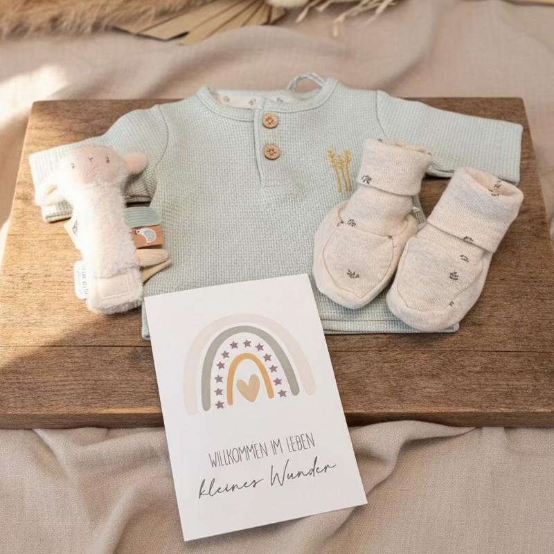 Frühchen Geschenkset mit mintgrünem Langarmshirt, Babyschuhen, Rassel, Grußkarte „Kleines Wunder“ und gratis Waschlappen liebevoll arrangiert auf Holzbrett
