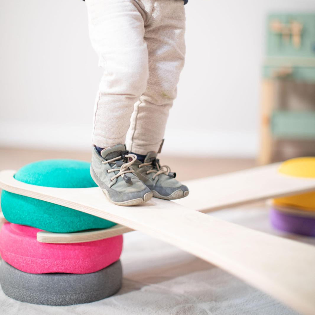 Kind auf tiSsi Balance Board zwischen Stapelsteinen