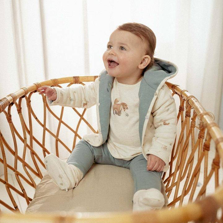 Baby sitzt im Korb und trägt die Little Dutch Wendejacke Stone Blue
