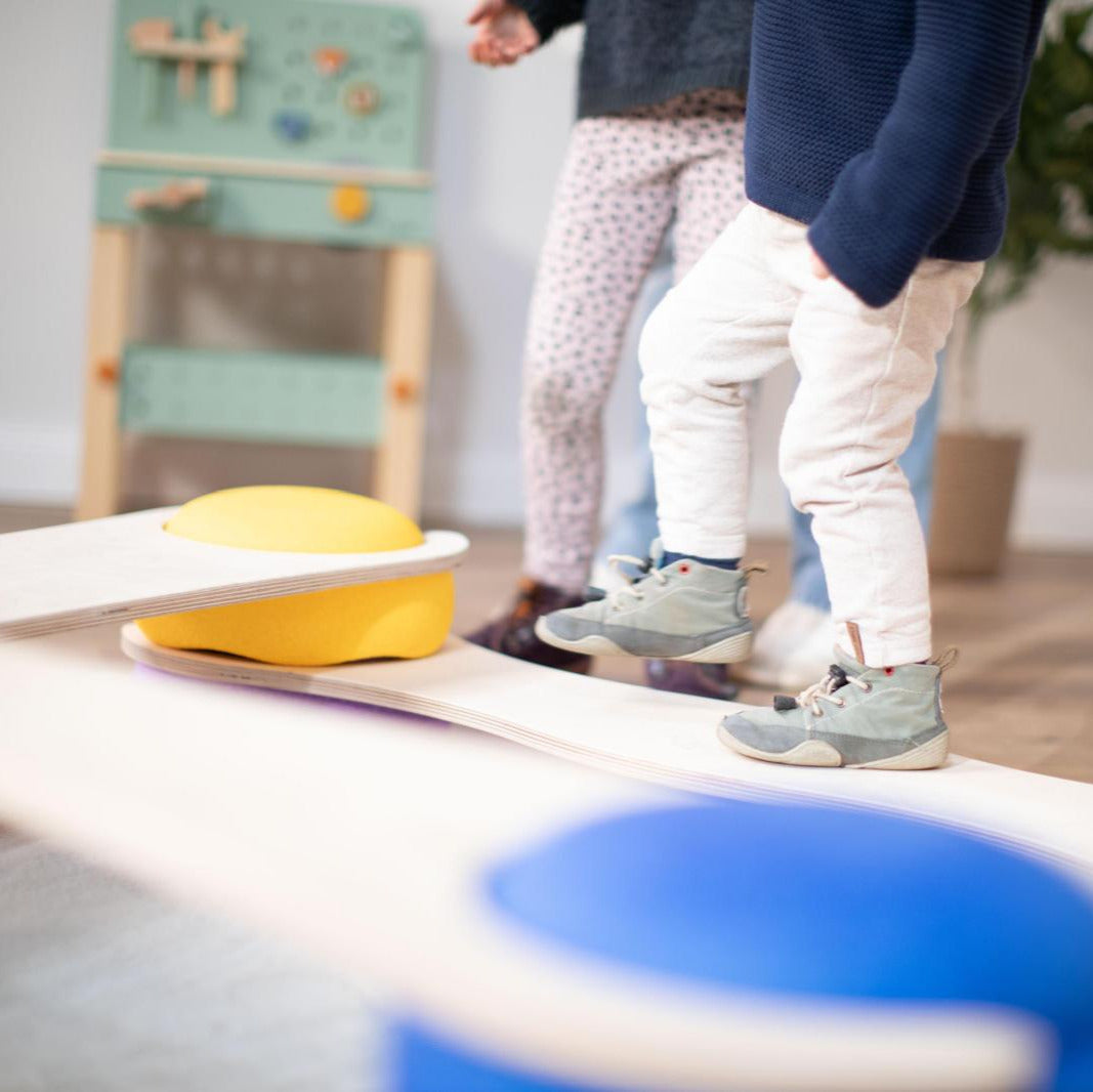 Kind balanciert auf tiSsi Balance Board mit Stapelsteinen